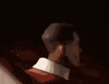 a close up of a man 's face in a dark room with a blurred background .