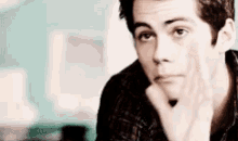 a man is sitting at a table with his hand on his chin .