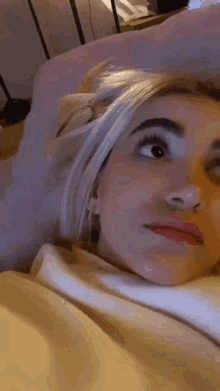 a woman is laying on a bed with her head on a pillow .
