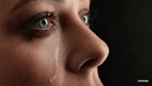a close up of a woman 's face with a tear running down her face .