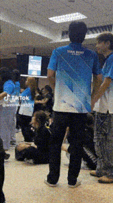 a man wearing a blue shirt that says swan dusit is standing in a crowd of people .