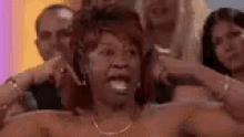 a woman is sitting in a bathtub with her mouth open and a group of people are behind her .
