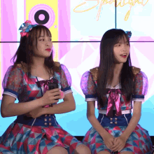 two girls are sitting in front of a wall with the word spotlight written on it