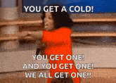 a woman in a red dress is holding a microphone and says you get a cold you get one and you get one we all get one