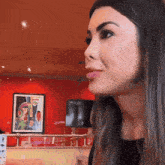 a woman sitting in front of a red wall with a picture on it that says ' coca cola ' on it