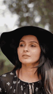 a woman wearing a black hat and a floral shirt
