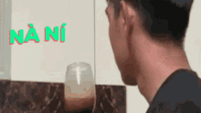 a man is looking at himself in a mirror while drinking a glass of coffee .