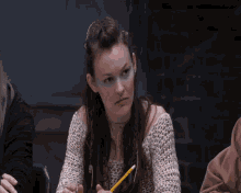a woman with blue makeup on her face holds a pencil