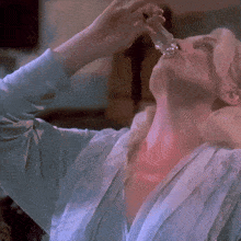 a woman drinking from a glass with a red glow around her neck