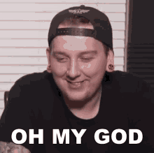 a man wearing a baseball cap and a black shirt is smiling and says oh my god
