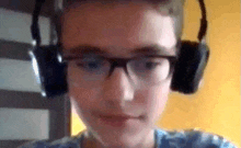 a young boy wearing glasses and headphones looks at the camera .