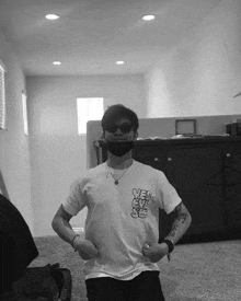 a black and white photo of a man wearing sunglasses and a white shirt that says " yes " on the back