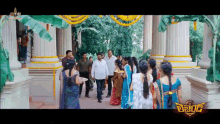a group of people are standing in front of a building with a sign that says ' telugu ' on it .
