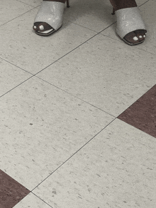 a woman standing on a tiled floor wearing sandals