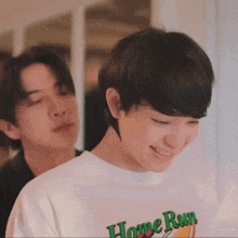 two young men are standing next to each other and one of them is wearing a t-shirt that says home run