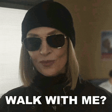 a woman wearing sunglasses and a beanie is asking to walk with her