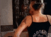 a woman wearing a black tank top with the word riot on the back