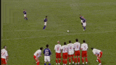 a group of soccer players are playing on a field with a net in the background