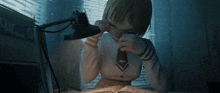 a girl sitting at a desk with a lamp and a book that says ' a ' on it