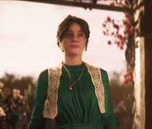 a woman in a green dress with a white lace vest and necklace