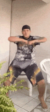 a man in a t-shirt and shorts is standing on one leg in front of a white chair .