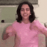 a woman in a pink shirt is sitting on a couch with her arms outstretched .