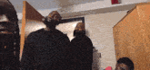 a group of men are standing in a room and one of them has dreadlocks