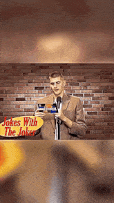 a man stands in front of a microphone with a sign that says jokes with the joker behind him