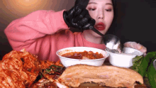 a woman wearing black gloves is eating food with a ladle
