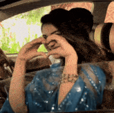 a woman in a blue dress is making a heart with her hands