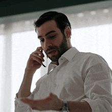a man in a white shirt is talking on a phone
