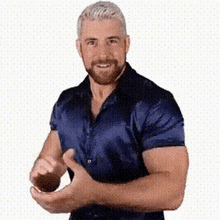 a man with a beard is wearing a blue shirt and making a funny face .