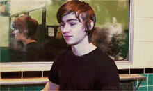 a young man in a black shirt is standing in front of a mirror with the word handler on it