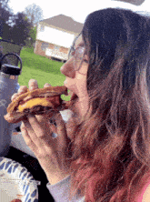 a woman with pink hair is eating a sandwich in a car