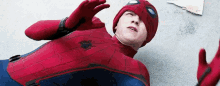a man in a spiderman costume is laying on the floor with his arms outstretched .
