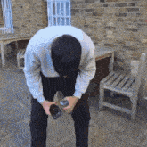 a man in a white shirt is kneeling down holding a bottle