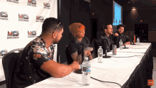 a group of people sitting at a table with bottles of water on it