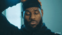 a man with a beard wearing a black headband with netflix on the bottom right