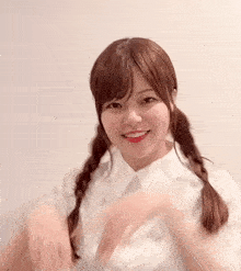 a woman with pigtails and a white shirt is smiling and waving