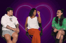 three people are sitting in front of a heart with a purple background