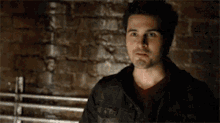 a man is standing in front of a brick wall .