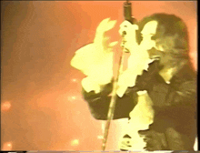 a man with long hair is singing into a microphone in a dark room