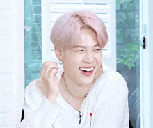 a man with pink hair and a white shirt smiles
