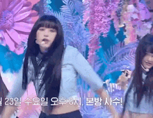 a group of young women are dancing on a stage in front of a purple background .