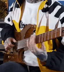 a man is playing a guitar in a yellow and black jacket .