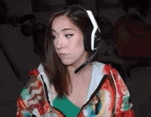 a woman wearing headphones and a colorful jacket is sitting in front of a computer screen .
