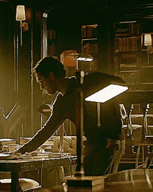 a man is sitting at a desk with a lamp on it in a dark room .