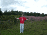 a man wearing a red vodafone shirt stands in a field