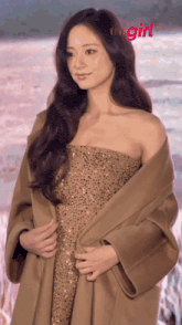 a woman in a strapless dress is standing in front of a body of water with elle girl written on the bottom