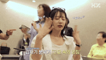 a woman with her eyes closed is surrounded by a group of people and a sign that says hz